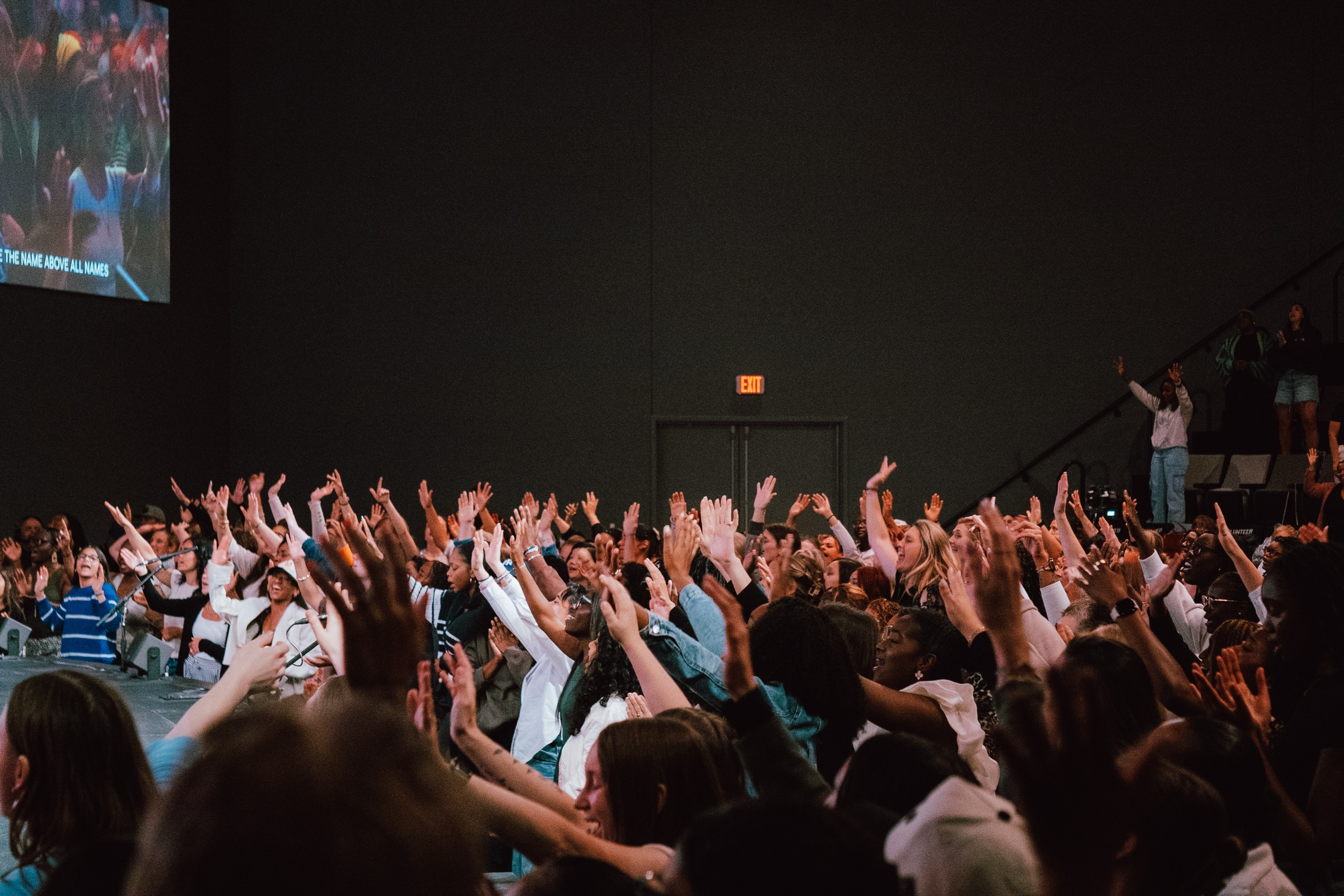 Women worshipping with hands raised at The Home Team Mom's Conference
